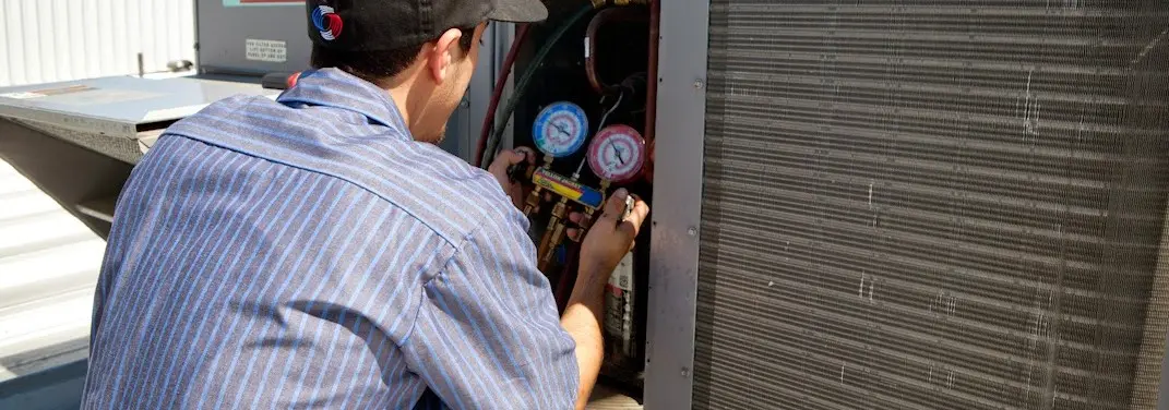 HVAC technician servicing a condenser unit in Margaret